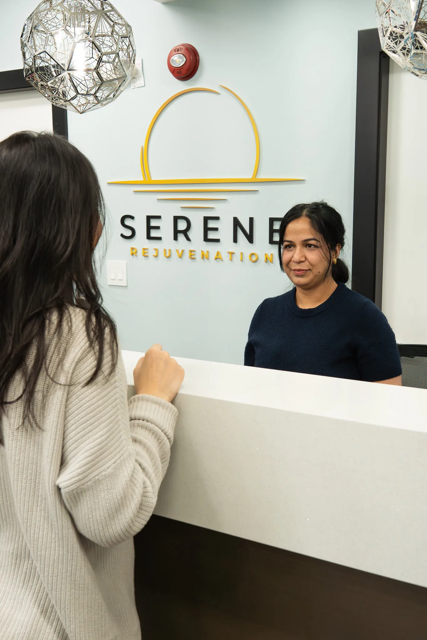 The Serene Rejuvenation front desk, with the clinic wordmark on the wall.