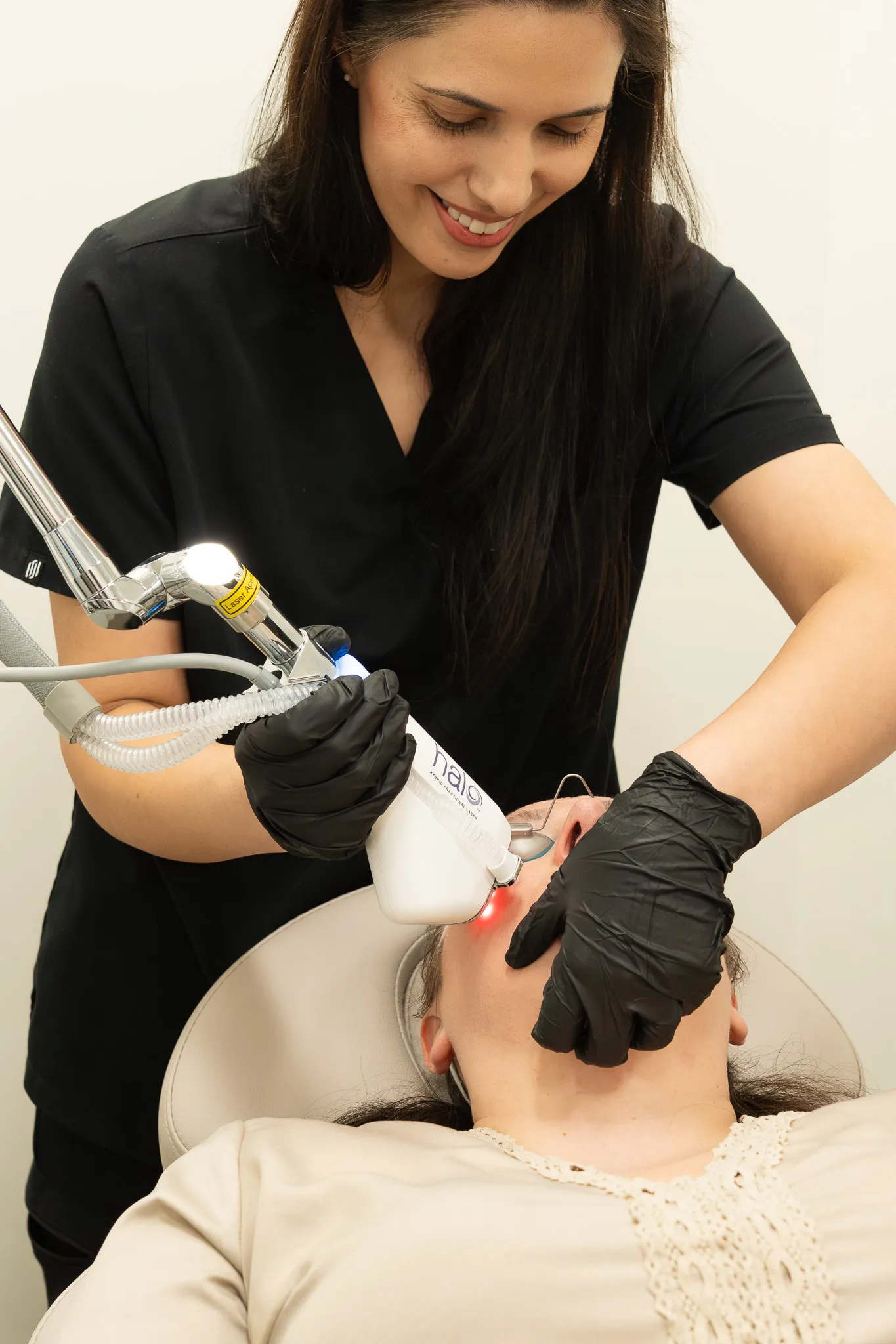 Dr. Sarai performs a HALO fractional laser treatment on a reclined patient.